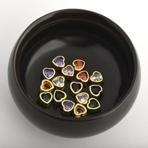 Macro view of assorted heart-shaped zircon charms in a ceramic bowl for DIY jewelry