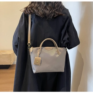Detail of grey-purple nylon tote bag with leather handles and detachable shoulder strap