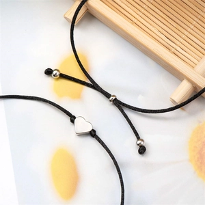 Détail du bracelet tissé noir ajustable avec cœur évidé argenté et perles en métal