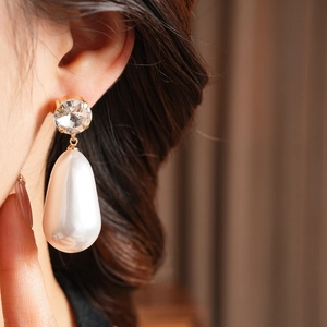Gros plan de boucles d'oreilles pendantes avec cristal rond et perle goutte sur un modèle