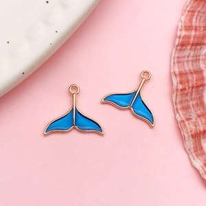 Detail view of two rose gold mermaid tail charms with blue enamel for DIY jewelry