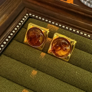 Detail of vintage square gold metal earrings with round amber resin in a velvet box