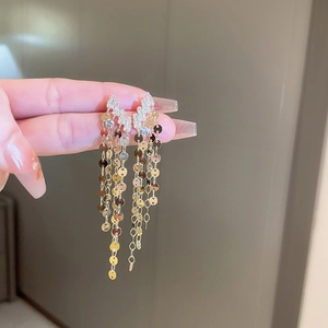 Detailed close-up of gold tassel earrings with glittering sequins and clear crystals