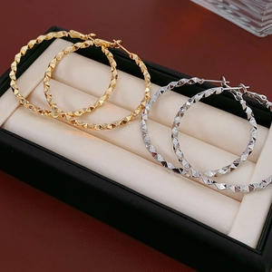 Close-up of gold and silver irregular round hoop earrings with diamond-cut texture