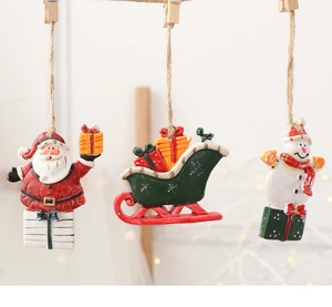 Detailed view of resin Christmas tree ornaments with Santa, snowman and red sleigh figurines