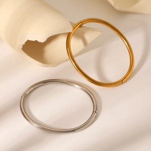 Minimalist stainless steel bangles in gold and silver finish on a decorative stone base