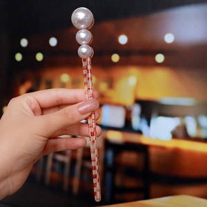 Detail of red checkered acetate hair stick with white faux pearl embellishments