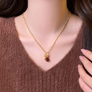 Detail shot of the red agate gourd pendant and 18k gold-plated chain on a brown sweater