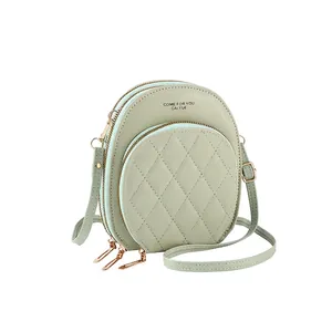 Detail of light green round crossbody bag featuring quilted pockets and triple zippers