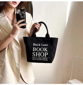Mirror selfie showing a black canvas tote bag with white Brick Lane Bookshop printing