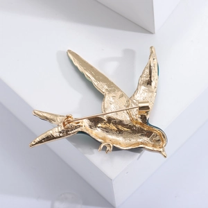 Detailed back view of a gold swallow brooch showing the safety pin and blue enamel wings