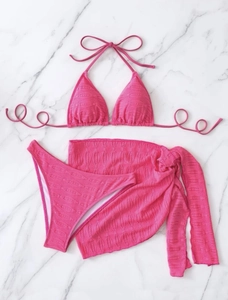 Flat lay of rose red three-piece bikini set including halter top and matching beach sarong