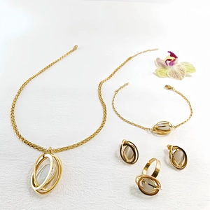 Detailed jewelry set showing gold-plated necklace, bracelet, studs and ring with white stones