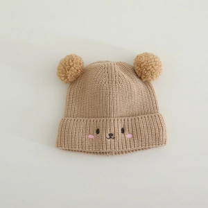 Close-up of soft knit texture and cute embroidered bear face on a brown baby hat