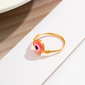 Detailed macro of pink evil eye bead on a handcrafted gold wire wrapped ring