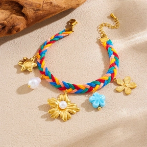 Close-up of rainbow braided bracelet with gold flowers, pearls, and blue floral charms