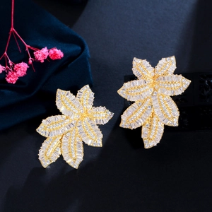 Close-up of gold leaf-shaped earrings with micro-set cubic zirconia on dark velvet