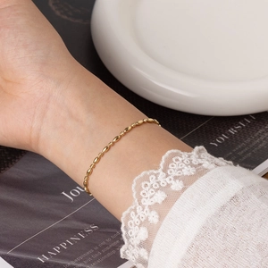Bracelet élégant en acier inoxydable plaqué or 18 carats porté au poignet d'une femme