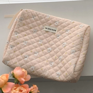 Detail of pink quilted cotton makeup bag featuring cute dog prints and a sturdy zipper