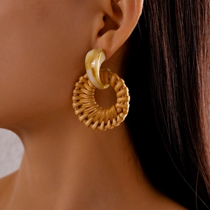 Close-up of bohemian resin marble drop earrings with woven rattan hoops on model
