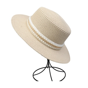 Detail of beige straw sun hat featuring elegant double-row pearls and a fine gold chain