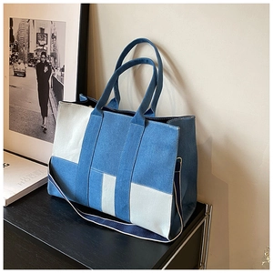 Detailed view of the patchwork denim tote bag with sturdy handles and wide shoulder strap