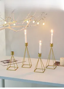 Detail of four gold geometric pyramid candle holders with burning spiral candles