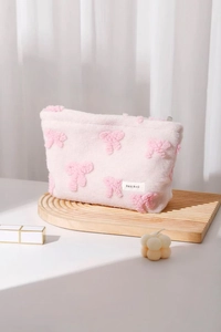 Detail of soft pink plush makeup bag with 3D bow pattern and H&R BAG brand label