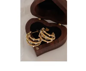 Close-up of gold twisted rope C-shape earrings with zircon inlay in a luxury jewelry box