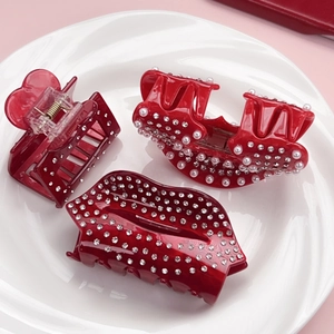 Lot de pinces à cheveux en acétate rouge avec strass et perles sur assiette blanche