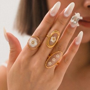Gold-plated ring set with resin flower charms and rhinestones worn by a model