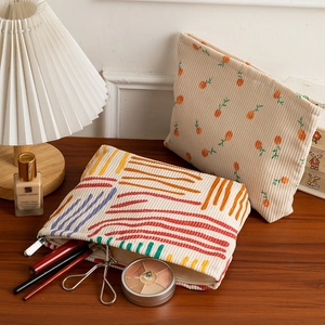 Detailed close-up of corduroy makeup bags with orange and wavy prints on wooden table