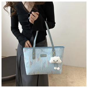 Detail of light blue tote bag featuring colorful embroidery and cloud plush pendant charm