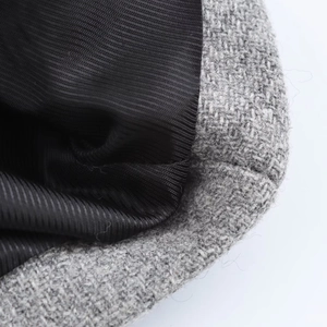 Close-up of grey tweed wool coat fabric with black twill lining and premium stitching