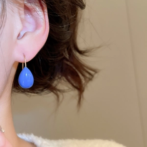 Vue macro d'une boucle d'oreille goutte en émail bleu pour un look chic et minimaliste