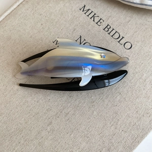 Detail of a pearl gradient whale hair claw clip with star embellishments and black base