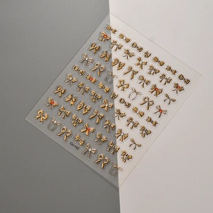 Detailed view of gold bow nail art stickers with rhinestones on a minimalist background