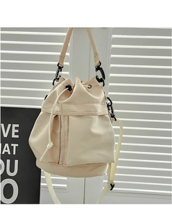 Detail view of beige nylon bucket bag featuring a drawstring closure and adjustable strap