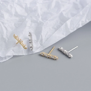 Detail view of gold and silver bar stud earrings with sparkling cubic zirconia stones
