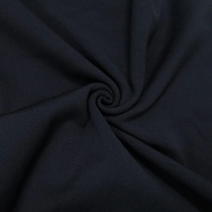 Macro detail of soft black fabric with spiral texture and draped folds for evening dress