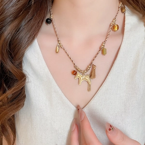 Close-up of golden woven necklace featuring horse pendant and colorful bead tassels