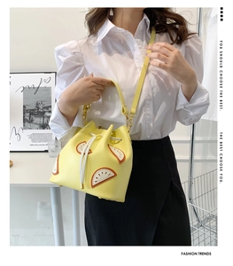 Detail of yellow bucket bag with lemon slice patch and adjustable strap on a white shirt