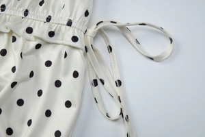 Detailed view of elastic gathered waist and side tie on a white polka dot skirt