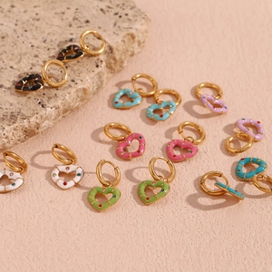 Close-up of heart-shaped drop earrings with colorful enamel and inset crystals