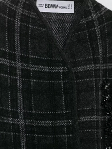 Detailed macro view of dark grey plaid knit fabric with exquisite black bead embellishments