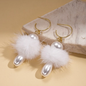 Detailed view of drop earrings with white pom-pom, faux pearls and gold hooks on marble