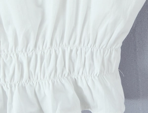 Detailed view of elastic smocking and pleated texture on white lace top and skirt set