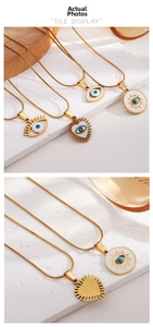 Macro shot of gold Evil Eye necklace charms with white enamel and blue crystal details
