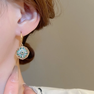 Macro shot of gold-plated flower earrings with blue and green zircon in vintage style