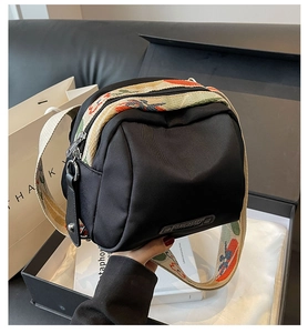 Close-up of black nylon crossbody bag featuring a colorful bohemian jacquard strap